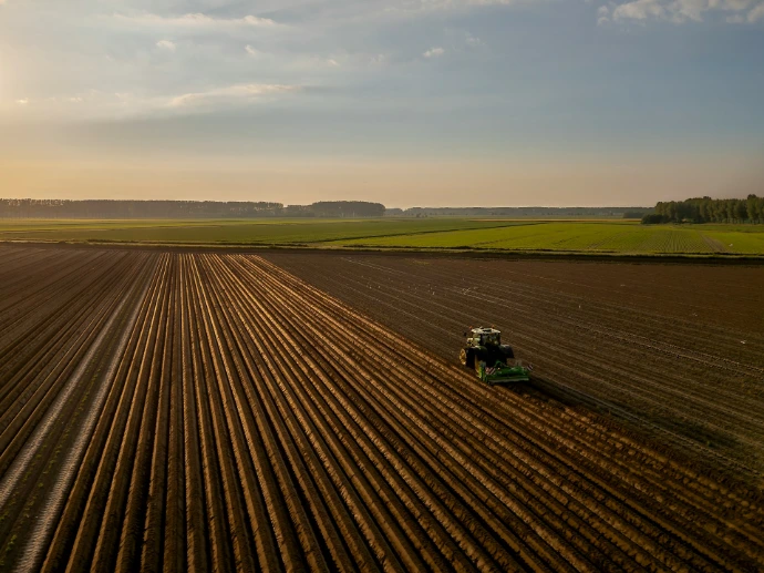 a tractor plowing a field at sunset